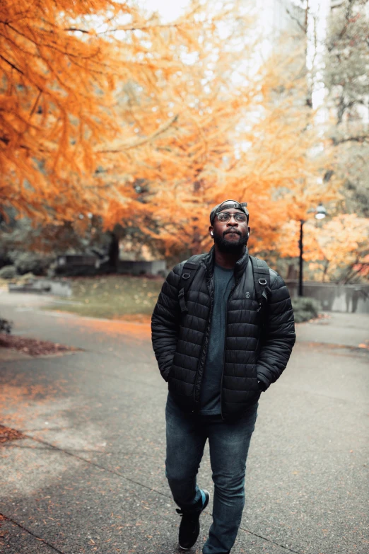 a man walking across a street next to trees