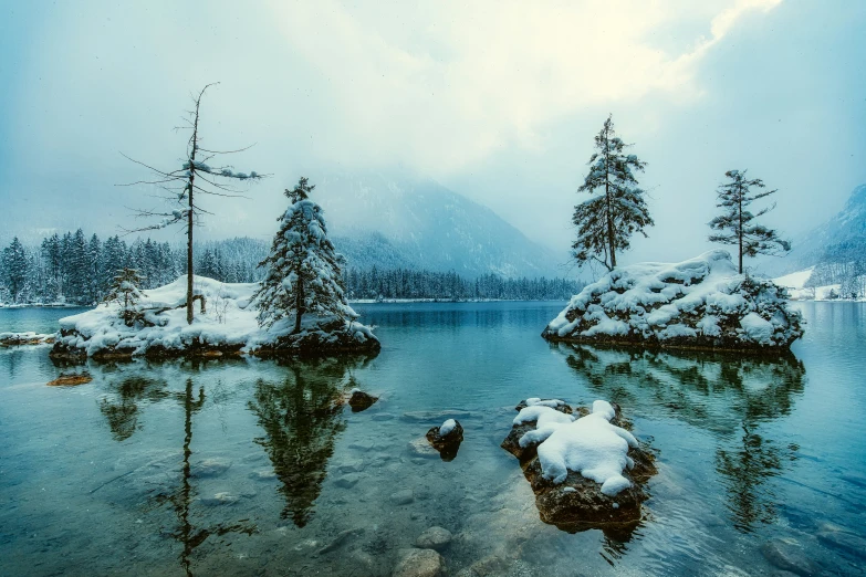 a lake is surrounded by snow and trees