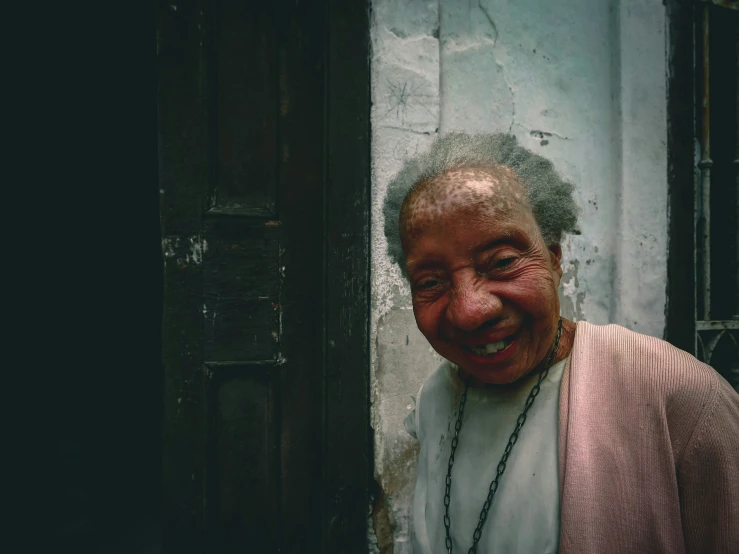 an older man smiles from behind a door