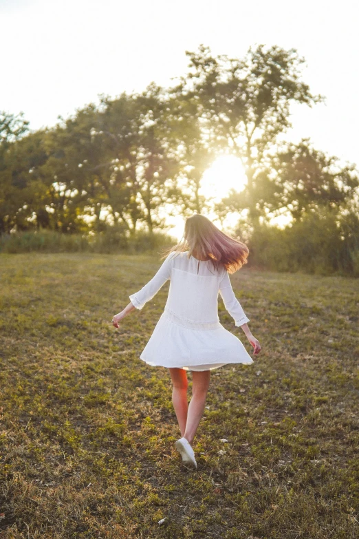 a girl running through a field toward trees