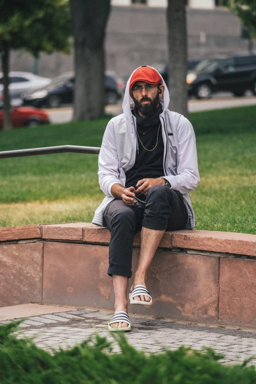 a person wearing a hoodie sits on a wall