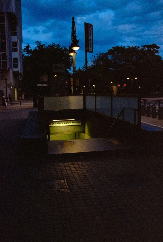 a city street with a lit light under dark skies