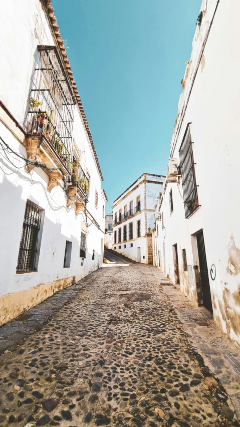 a narrow stone street with white buildings in a small village