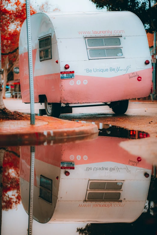 a pink and white camper sits in a flooded area