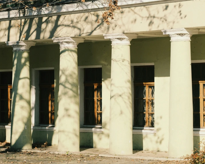 a man walking past a yellow building in front of some trees