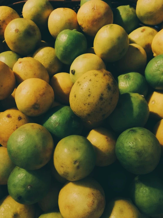 yellow and green lemons stacked together in a pile