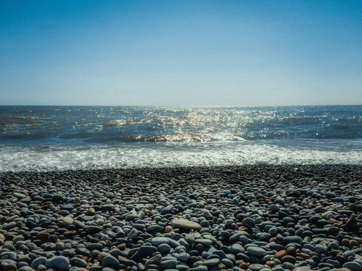 the sun is shining on the water and rocks at the beach