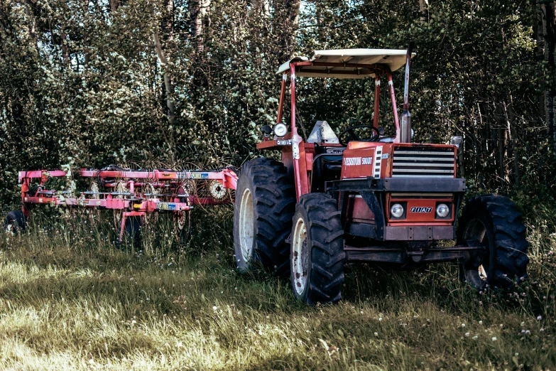 a red tractor in some grass and trees