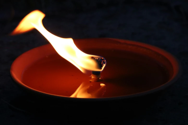 a red and yellow fire bowl with a lit candle burning in it