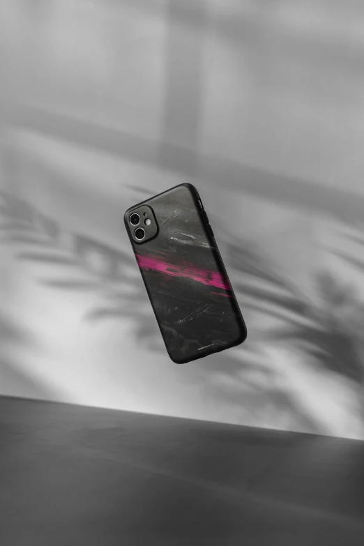 a cell phone sitting in the air with its back half covered by pink and black