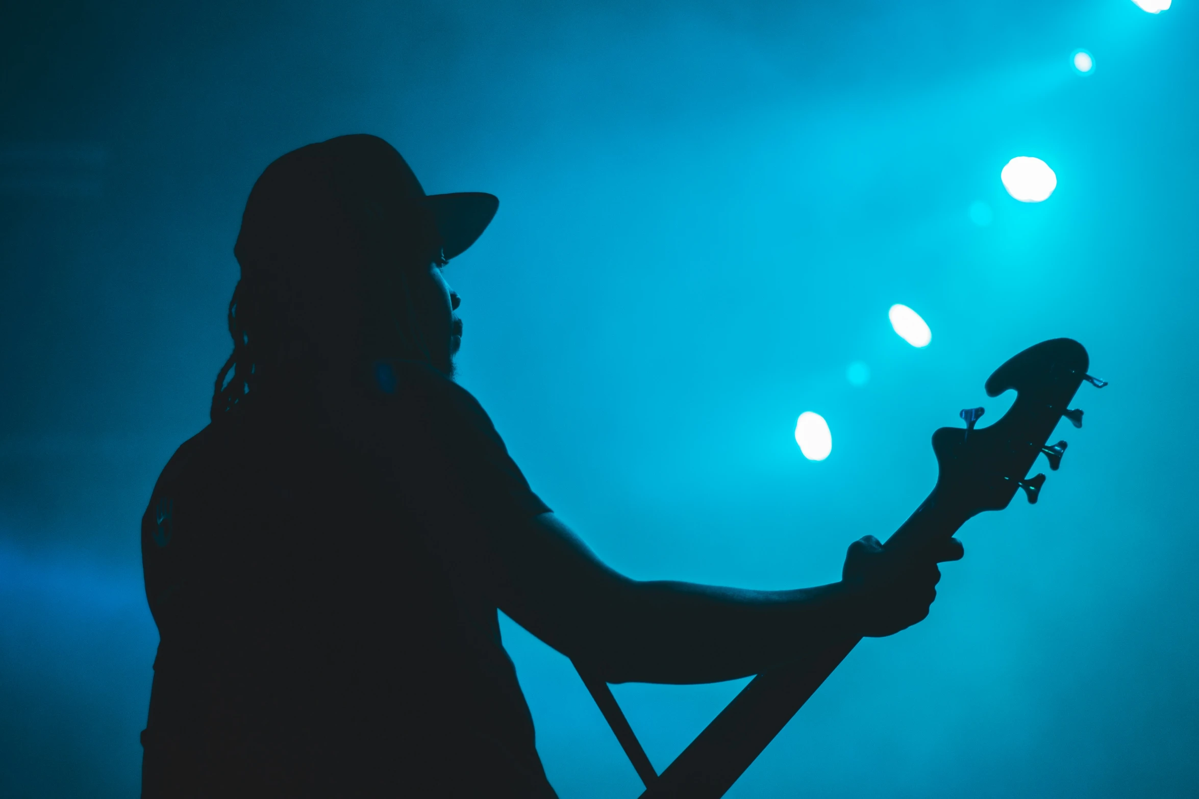 a man holding a guitar at night against a blue light