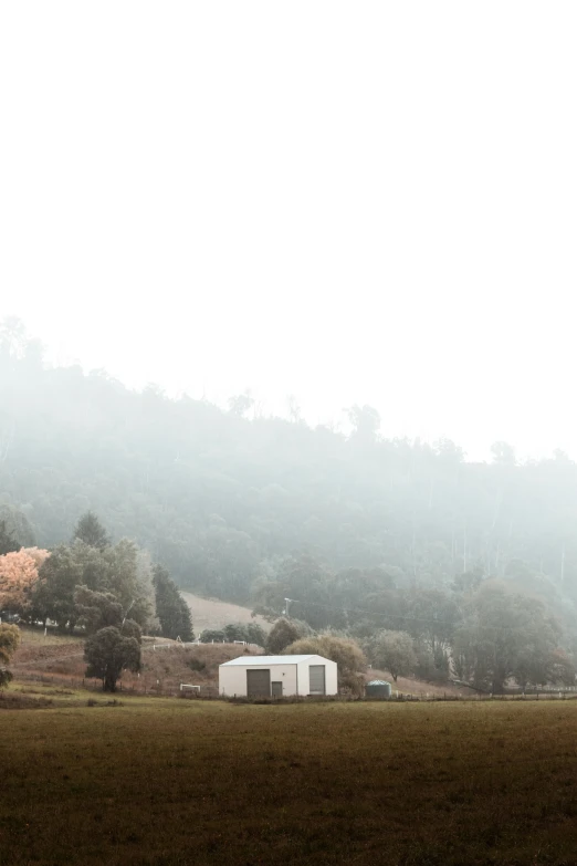 the farm with a small structure on it sits in front of mountains