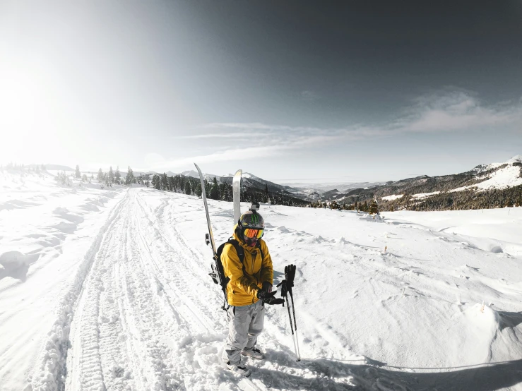 a man in yellow jacket on skis standing on a snowy road