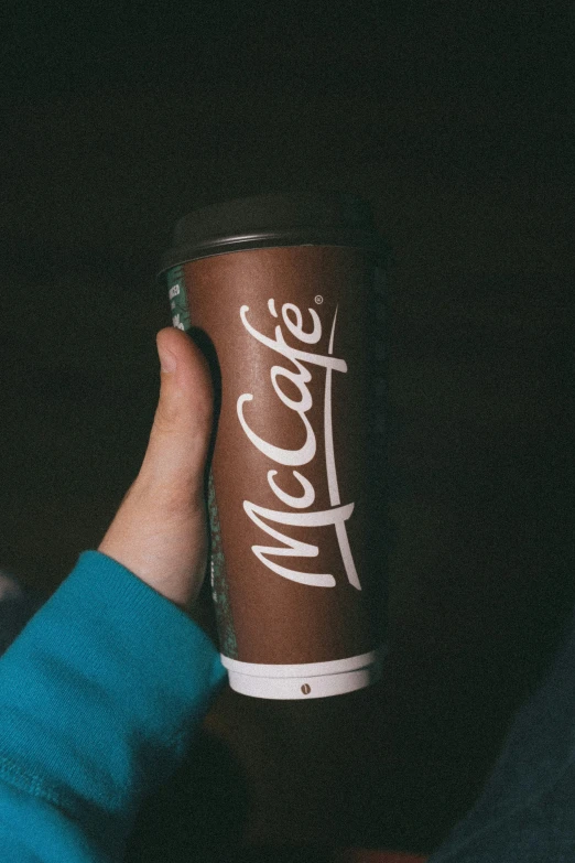 a person holding a cup with a coca - cola logo