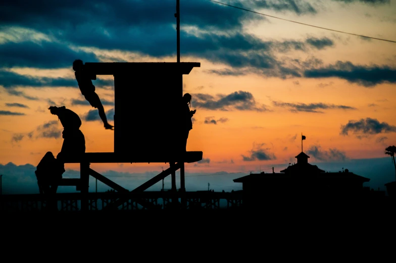 people in lifeguard chairs on the beach at sunset