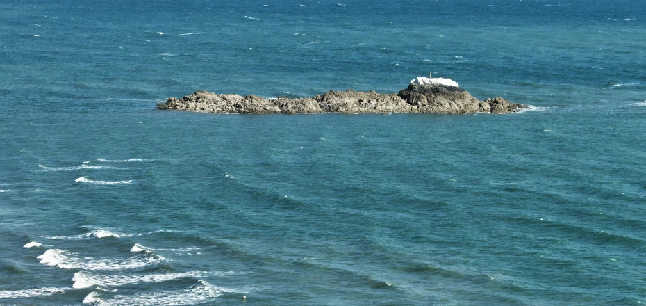 an island made of rock is in the ocean