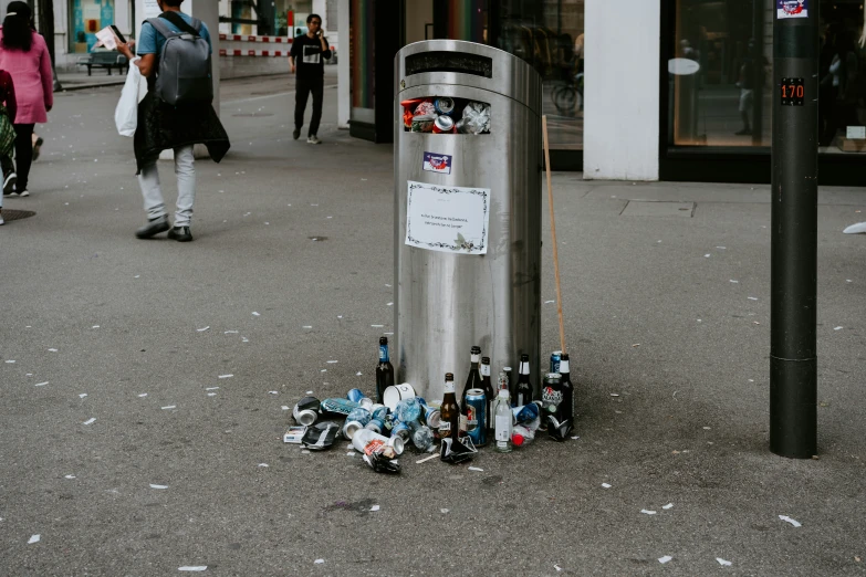 a bunch of beer bottles are sitting in a street trash can