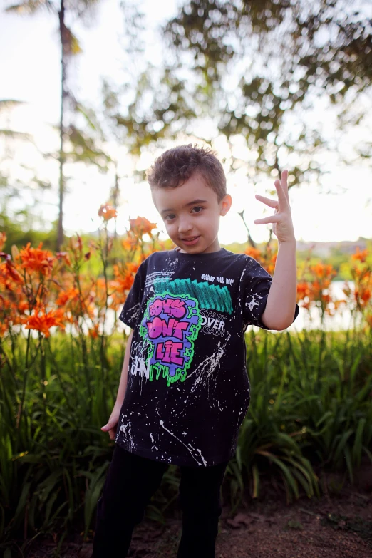 small child in t - shirt near flower garden at sunset