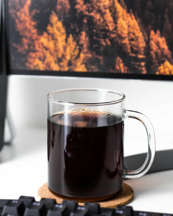 a cup of black coffee sitting on top of a wooden coaster