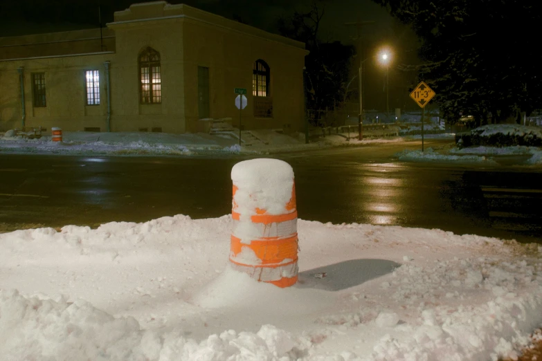 an orange and white cone sits on top of some snow