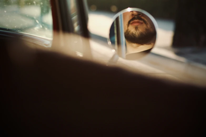 a man's reflection is in the rear view mirror