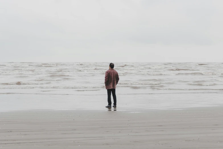 a man standing at the shore looking out to sea