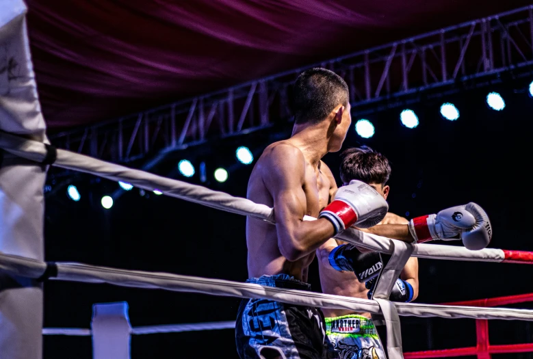 two male boxers in the ring, one looking at his bag