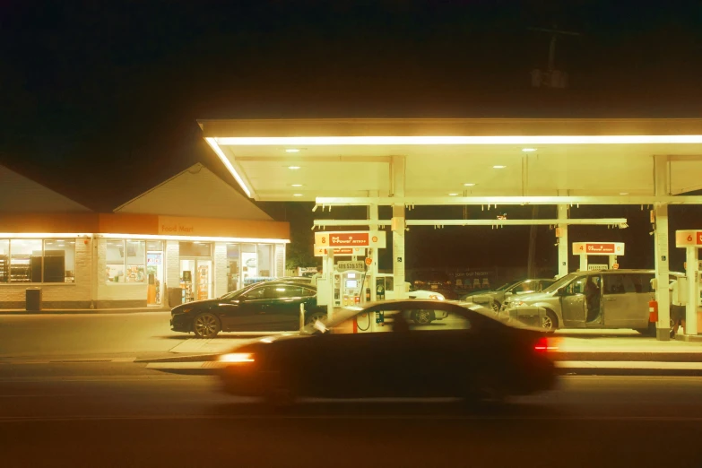 a dark picture of an gas station with a few cars waiting