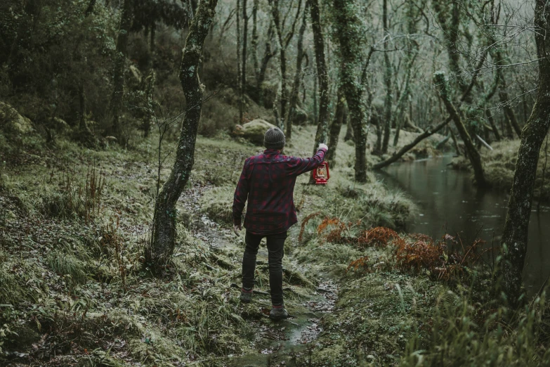 a man standing in the woods holding an umbrella