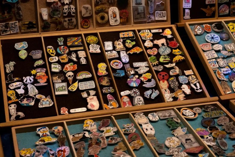 there are various pins, badges, and earrings in a box