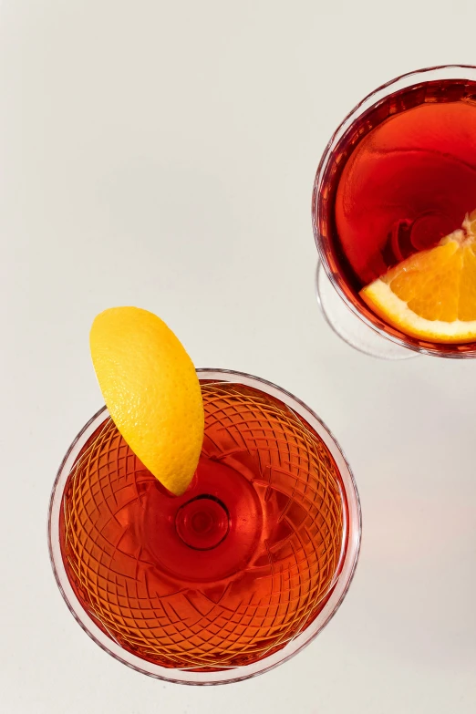 two different glasses with oranges in them and one of them being filled with liquid