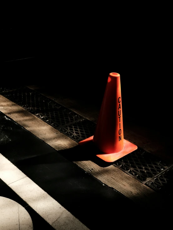 an orange traffic cone sitting next to a sidewalk
