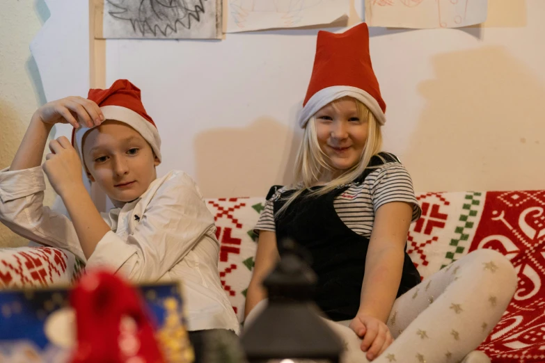 two s wearing christmas hats on a couch