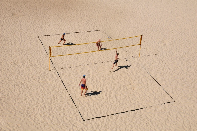 four people playing volleyball in the sand on a beach