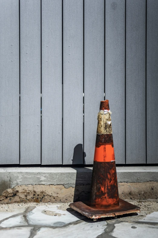 an orange and gold cone next to grey fence