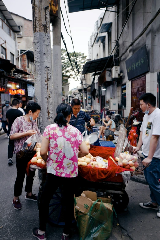 a person stands next to a cart selling produce