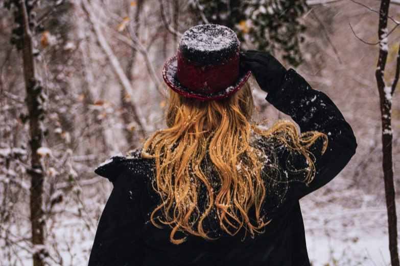 a young woman in a red hat stands in the snow