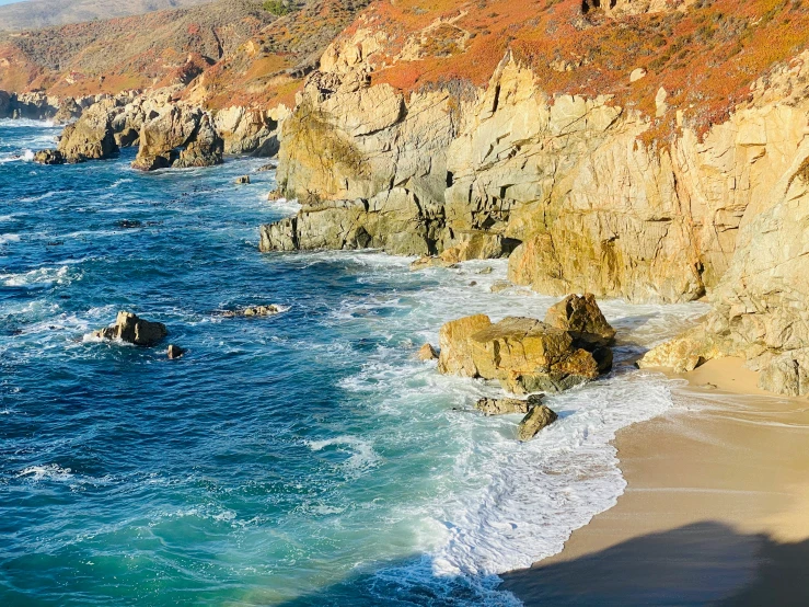 some water some rocks and water waves and orange cliffs