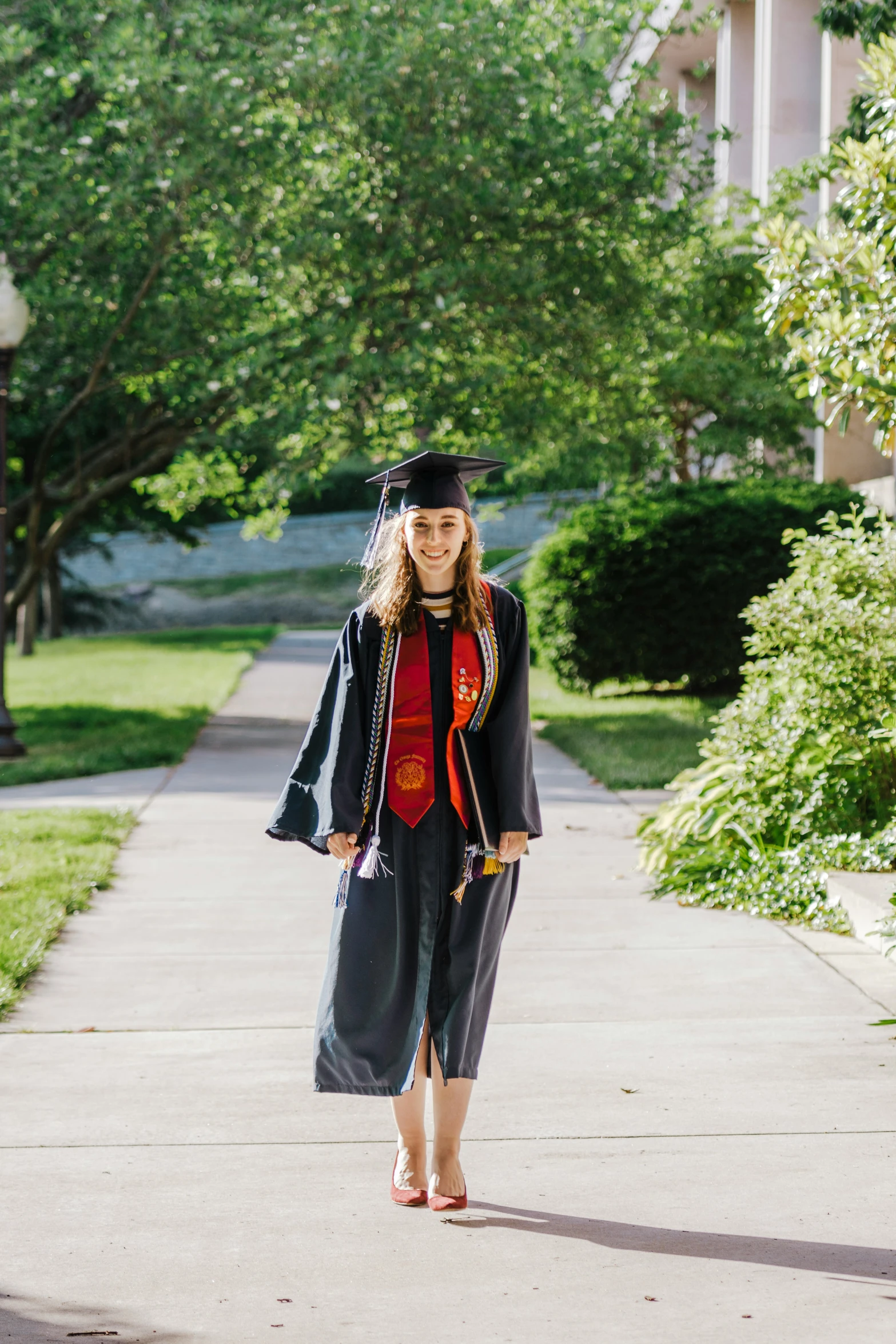 girl in graduation robe walking along a path