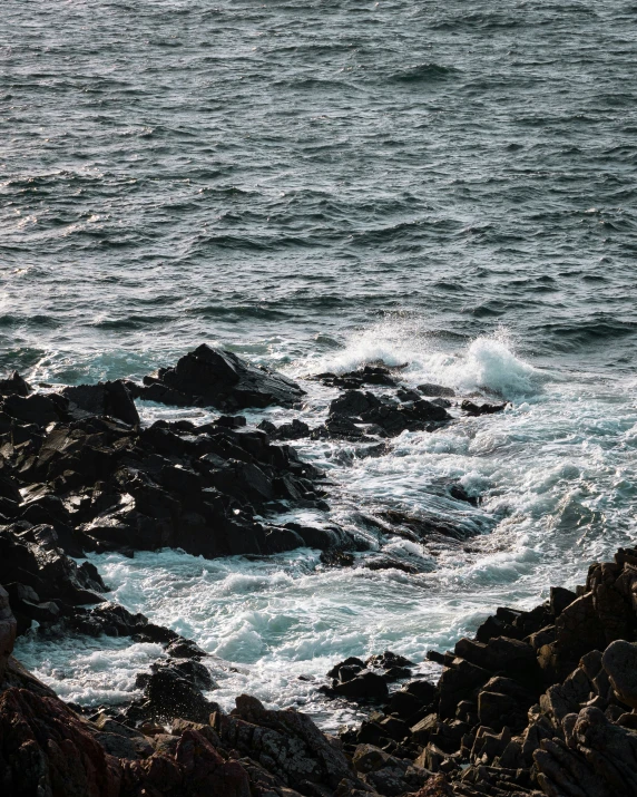 the surfer is standing on rocks near a large body of water