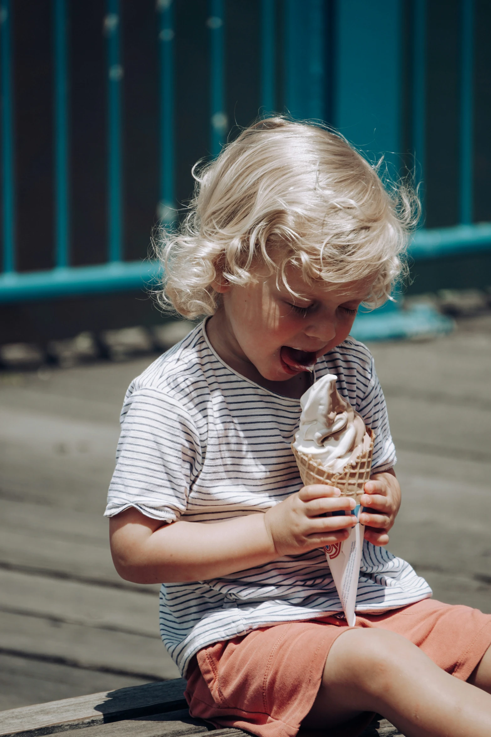 a small  sitting down eating an ice cream cone