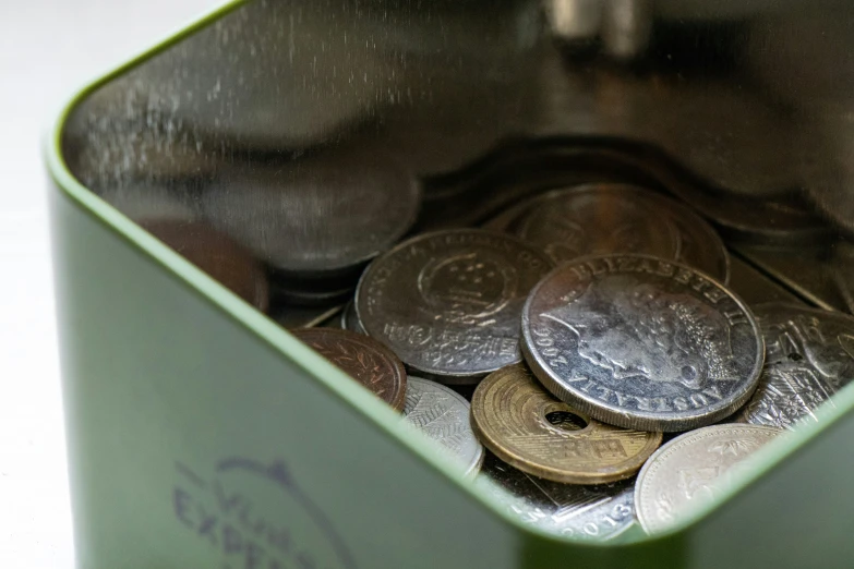 a green bin with coins inside and some on the floor