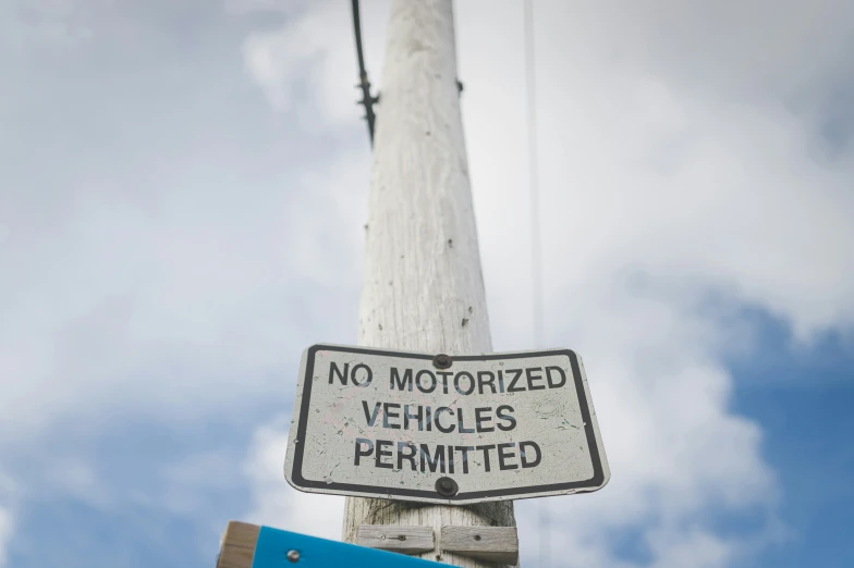 an old telephone pole is damaged and has a sign stating no motorized vehicles permitted