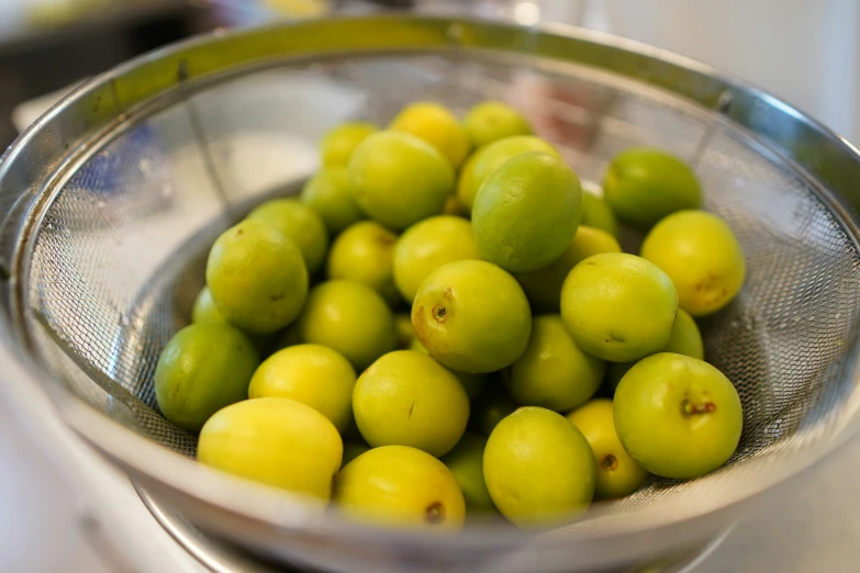 the fruit is in the metal colander with a strainer