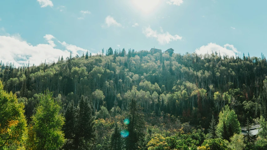 mountains are covered in trees and clouds in a blue sky