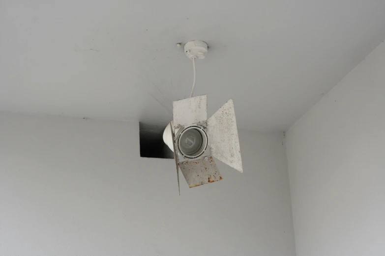 an air vent in the ceiling and a wall light inside a white walled room