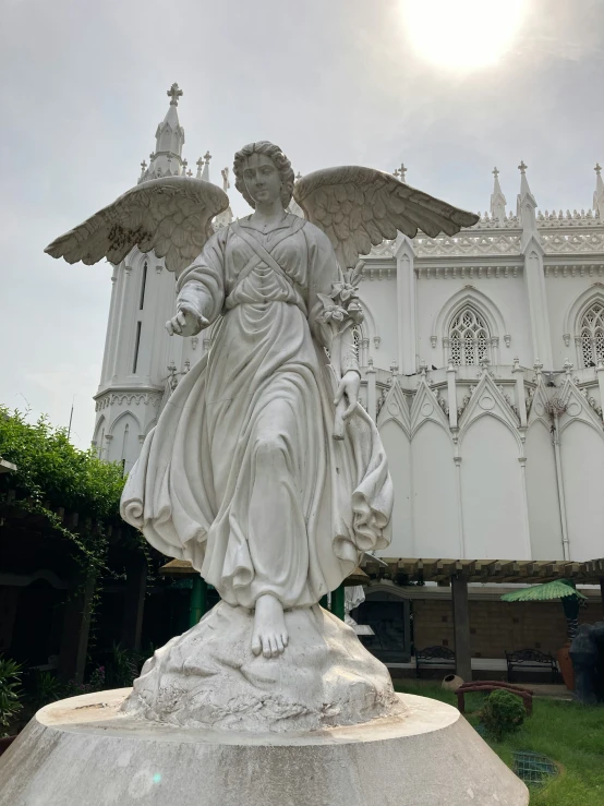 a statue of an angel in front of a white building