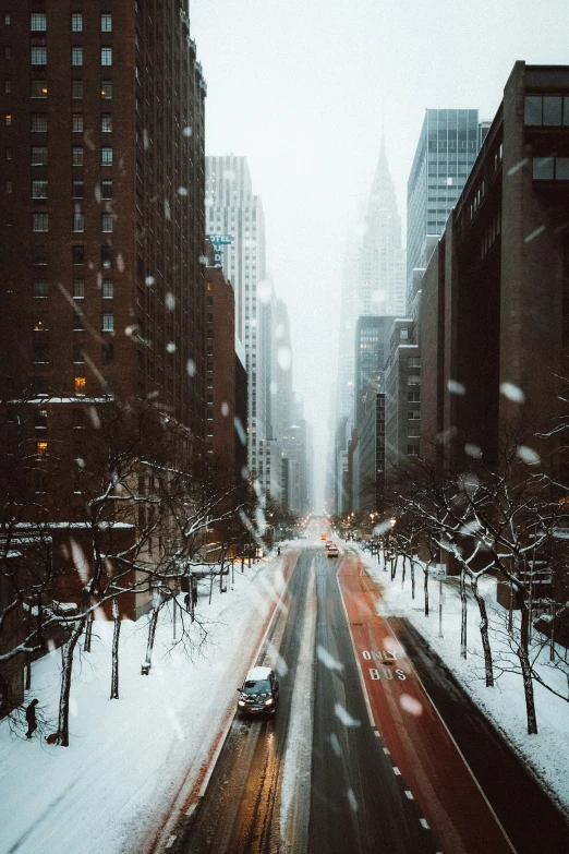 a car on a snowy street surrounded by high rise buildings