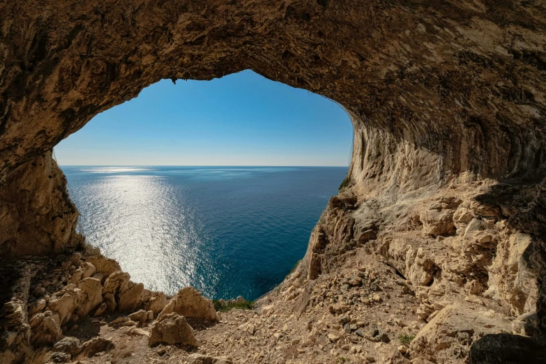 the ocean from inside a large cave with a clear sky