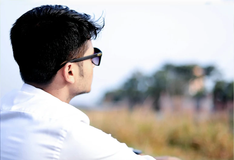 a young man sits in the sun looking out to sea